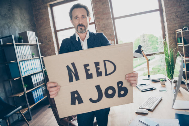 Photo of despair sad layoff dismissed handsome worker mature jobless guy hold placard poster search job last work day world crisis ruined career workplace fired bad mood modern office indoors - Photo, image