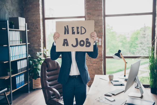 Photo of moody despair laid off office worker mature guy hiding closing face placard poster looking for new job unemployed concept workplace fired bad mood stand modern office indoors - 写真・画像