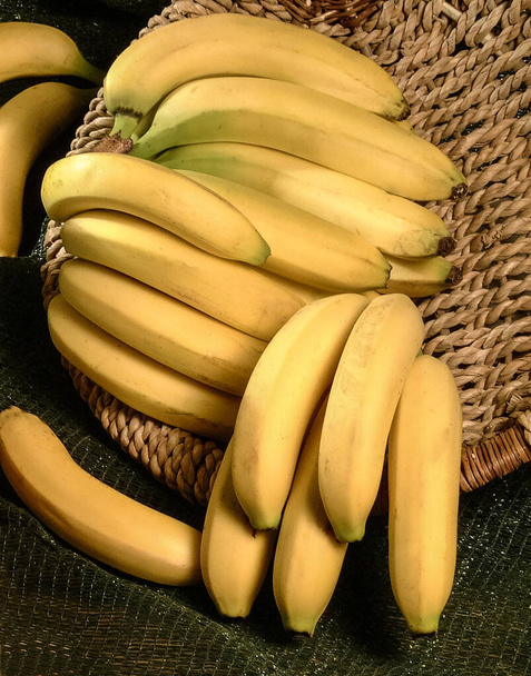 Вирізані банани в плетеному кошику на зеленому тлі. крупним планом
. - Фото, зображення