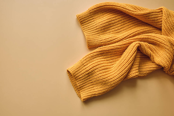 Jersey de punto de otoño naranja amarillo para mujer sobre fondo beige pastel. Concepto de ropa creativa, moda otoño invierno acogedor jersey. Moda femenina, descuentos de otoño. Compras - Foto, Imagen