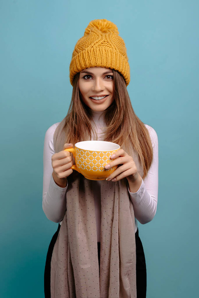 Frau mit gelbem Schal und wintergelbem Hut, die in die Kamera lächelt - Foto, Bild
