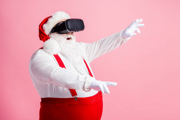 Profile side view portrait of his he nice attractive bearded fat overweight Santa watching vr wear futuristic innovation helmet device enjoying realistic illusion isolated pink pastel color background - Zdjęcie, obraz