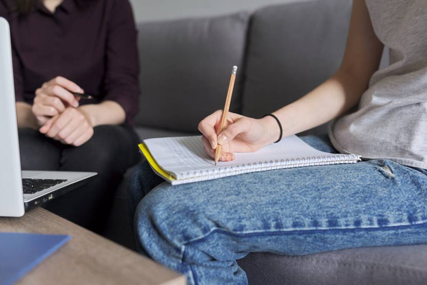 Primer plano de los estudiantes que estudian individualmente con el profesor, se centran en las manos con cuaderno y lápiz - Foto, imagen