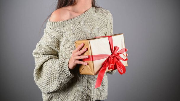 Ragazza che regge un regalo con un maglione a maglia. Foto di alta qualità - Foto, immagini