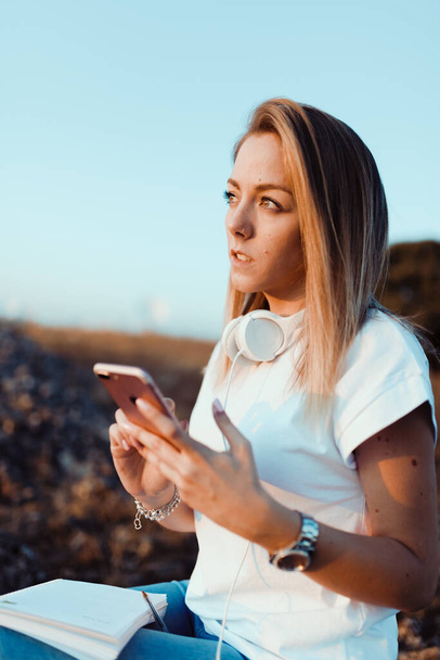 Young woman taken notes on her smartphone in the field - Photo, Image
