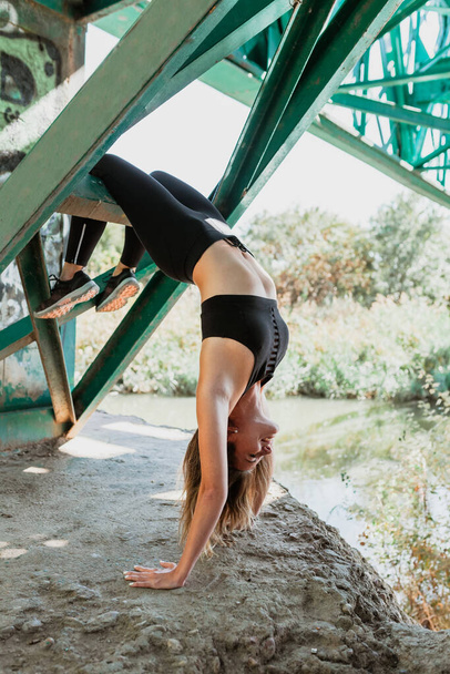 Woman does contortionism on an abandoned bridge - Foto, afbeelding