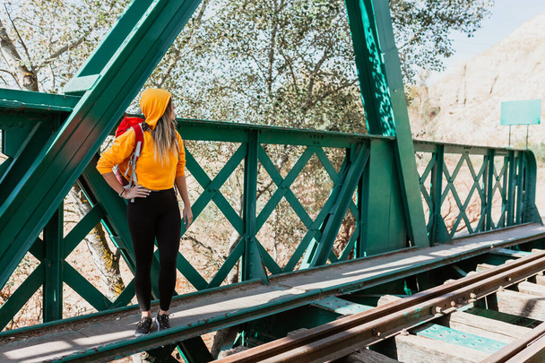 Жінка досліджує стежки і старий залізний залізничний міст
 - Фото, зображення