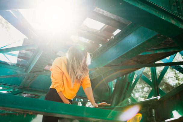 Mujer escalando entre vigas de hierro del viejo puente ferroviario - Foto, imagen