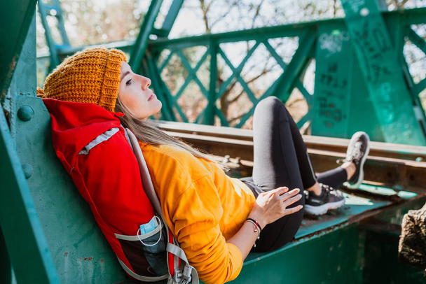 Trekking de mujer descansa en un viejo puente ferroviario abandonado - Foto, imagen