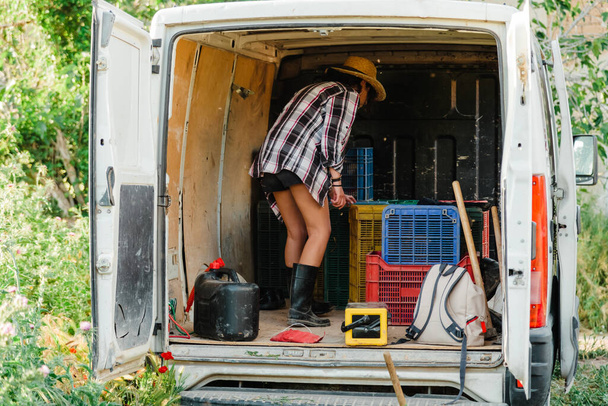 Young farmer woman looking inside a van with hoe - Foto, Imagem