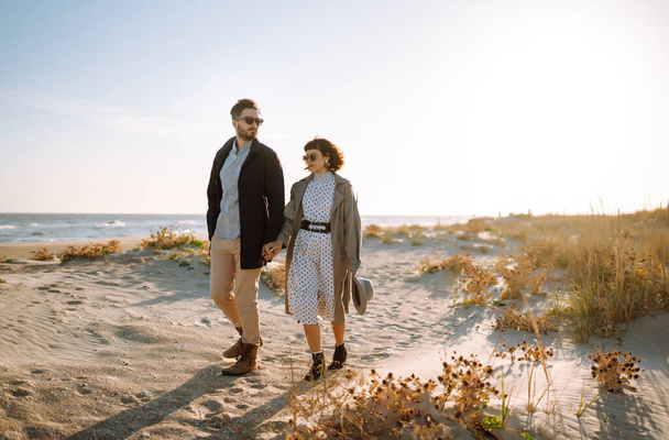Young loving couple walking and hugging by the sea. Enjoying time together. Fashion, lifestyle and autumn mood. - Foto, Imagem