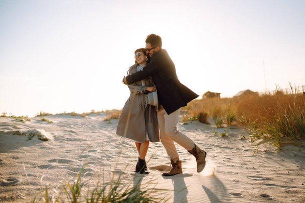 Young loving couple walking and hugging by the sea. Enjoying time together. Fashion, lifestyle and autumn mood. - Foto, imagen