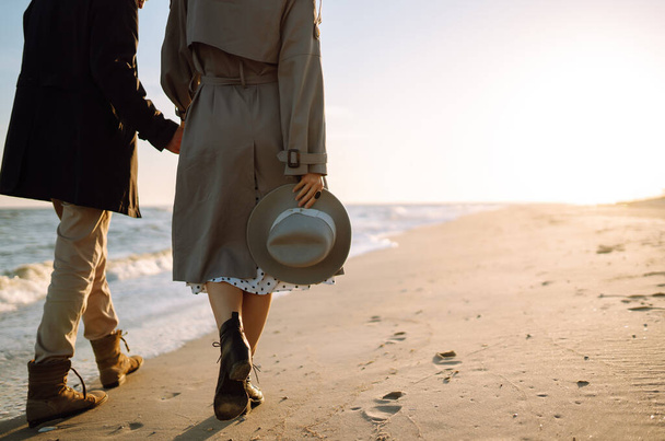 Young loving couple walking and hugging by the sea. Enjoying time together. Fashion, lifestyle and autumn mood. - 写真・画像