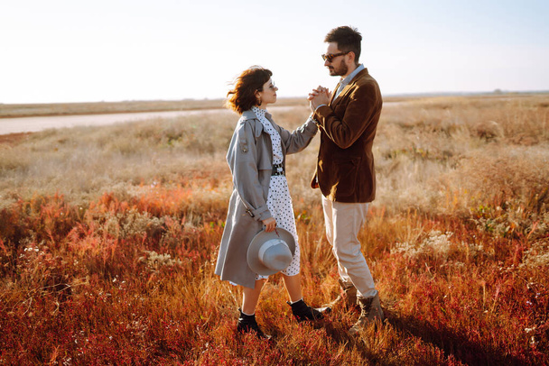 Young loving couple walking and hugging in autumn field. Enjoying time together. Fashion, lifestyle and autumn mood. - Fotó, kép