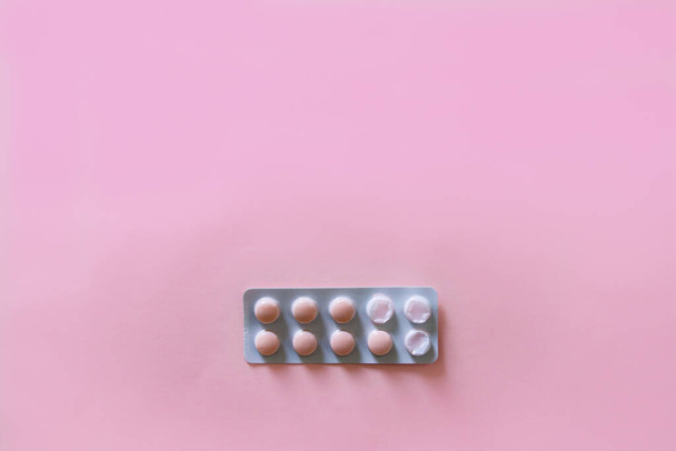 λευκές και ροζ κάψουλες στο ροζ φόντο. Πάνω άποψη, επίπεδη lay, μινιμαλισμός. φάρμακο. - Φωτογραφία, εικόνα