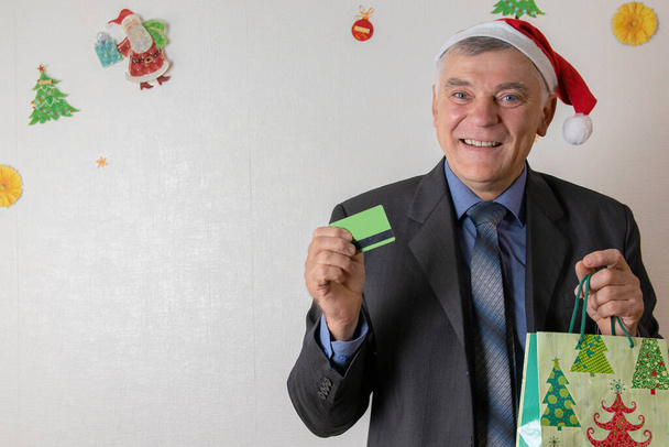 Szczęśliwy człowiek z kartą kredytową i telefonem komórkowym dokonuje zakupów na Święta i Nowy Rok. Prezenty świąteczne i noworoczne. zakupy elektroniczne w sklepie internetowym. - Zdjęcie, obraz