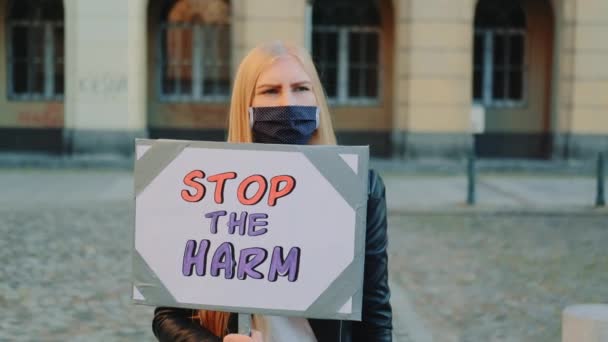 Blondynka w masce ochronnej protestująca przeciwko szkodzie trzymając parowiec - Materiał filmowy, wideo