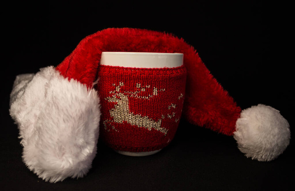 bicchiere di Natale bianco con un cappello di Natale su sfondo nero - Foto, immagini