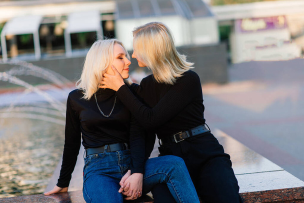 Twee jonge vrouwen wandelen glimlachend omhelzen en kussen outdoor - Foto, afbeelding