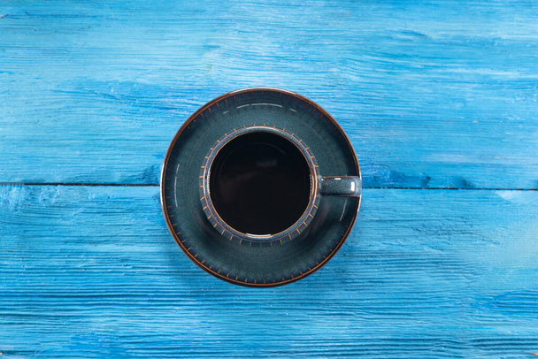 Czarna kawa w filiżance na niebieskim drewnianym tle stołu. - Zdjęcie, obraz