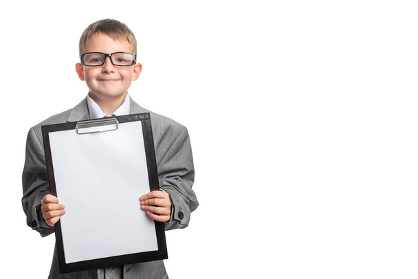 Malé dítě oblečené v obchodním obleku a brýlích jako podnikatel s psacím stolem. Dítě v otcově obleku a prázdný list papíru ve schránce izolované na bílém pozadí. - Fotografie, Obrázek