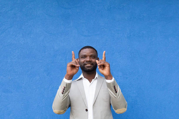 o afro-americano mostra mãos para cima no fundo azul - Foto, Imagem