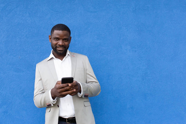 ο ευτυχισμένος Αφροαμερικανός με το τηλέφωνο στο μπλε φόντο - Φωτογραφία, εικόνα