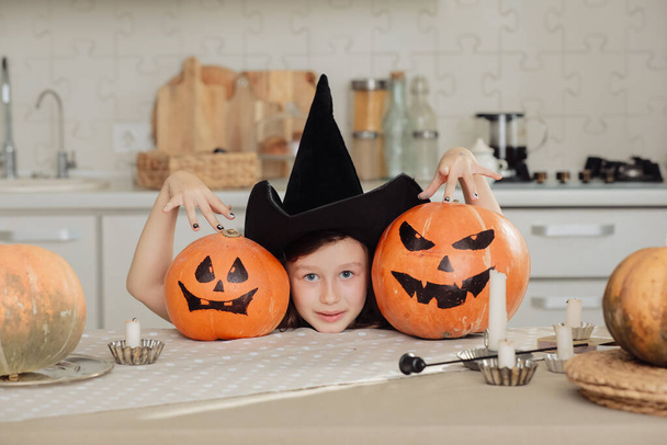 Boldog Halloweent! Aranyos kislány boszorkányjelmezben, faragott sütőtökkel. Boldog családi felkészülés Halloweenre - Fotó, kép