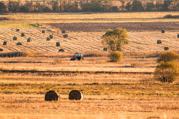 Lonely tractor cosecha heno campo de cultivo rastrojo amarillo dorado naranja otoño montaña fondo masivo bulgaria tecnología máquina agricultura copiar espacio para texto - Foto, imagen