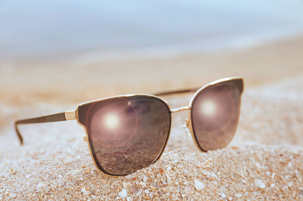 Stylish sunglasses on sandy beach, closeup view - Fotó, kép