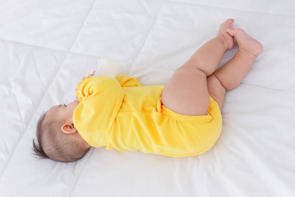 Азійське немовля спить на ліжку і смокче молоко.. - Фото, зображення