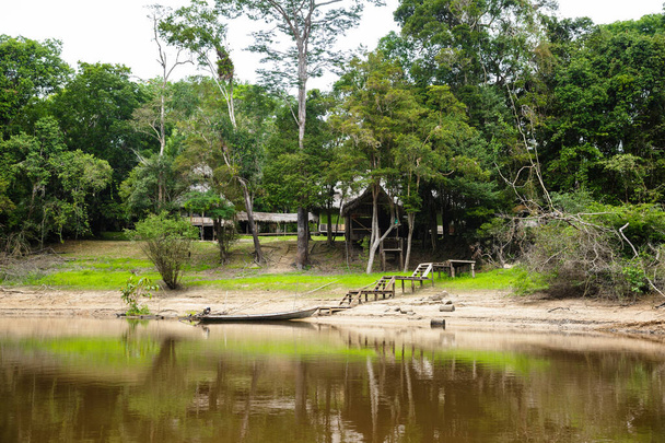 Kép a perui dzsungelben, közel az Amazon folyóhoz. Hagyományos faház. Nyugodt víz, fák, fa. - Fotó, kép