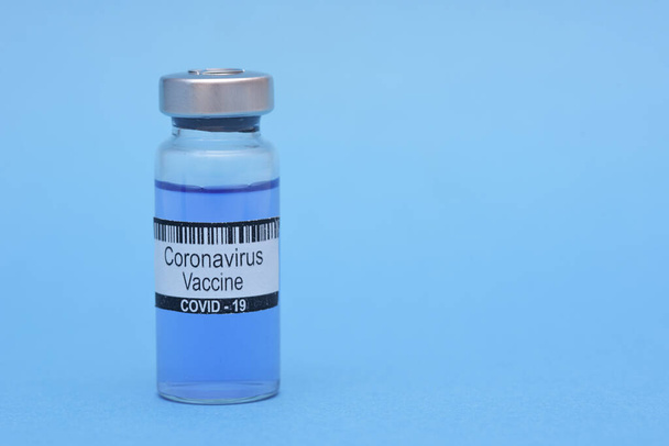 Coronavirus vaccine in bottle on blue background with space for text. Victory over Corona virus SARS-CoV-2 epidemic, scientists have found vaccine against coronavirus SARS-COV2. High quality photo - Fotó, kép