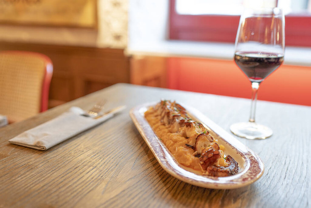 A closeup of a tasty octopus and mash dish accompanied by red wine - Valokuva, kuva
