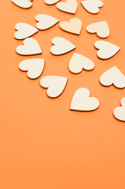 A closeup of the wooden shaped hearts on the orange surface - space for text - Foto, Imagen