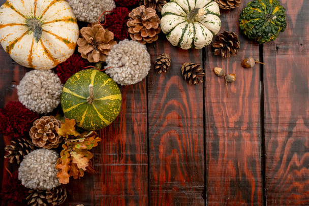 An overhead shot of various pumpkins and pinecones on wooden surface with space for your text - autumn themed background - Foto, imagen