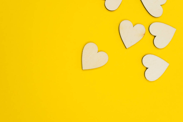 A top view of the wooden shaped hearts on the yellow surface - space for text - Фото, изображение