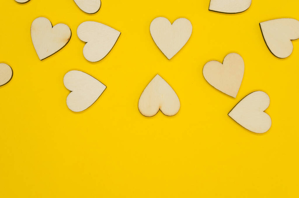 A top view of the wooden shaped hearts on the yellow surface - space for text - Foto, Imagen