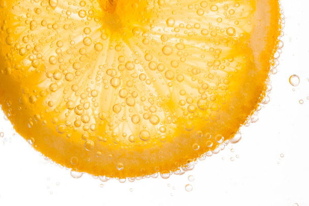 close-up of lemon slice in clear water with bubbles - Foto, afbeelding