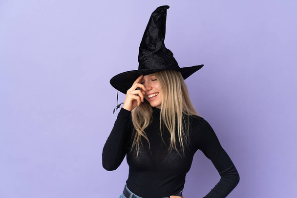 Young woman with witch costume over isolated background laughing - Фото, изображение