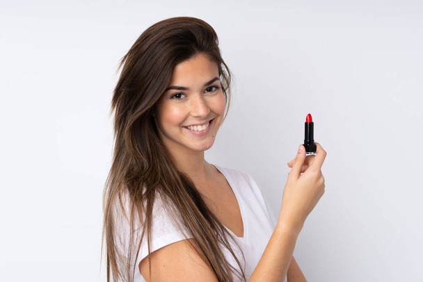 Adolescente chica sobre aislado fondo sosteniendo rojo lápiz labial - Foto, Imagen