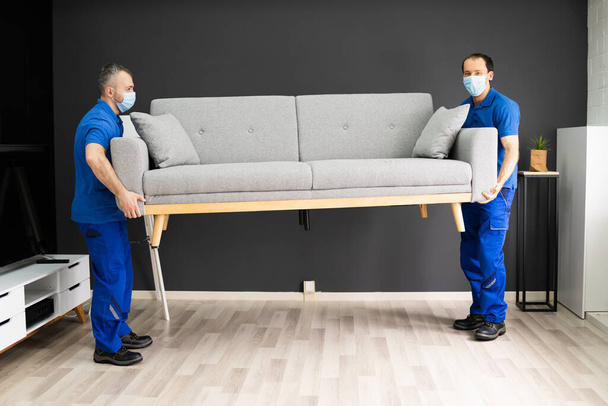 Professional Movers Moving Couch Furniture In Face Mask - Foto, afbeelding