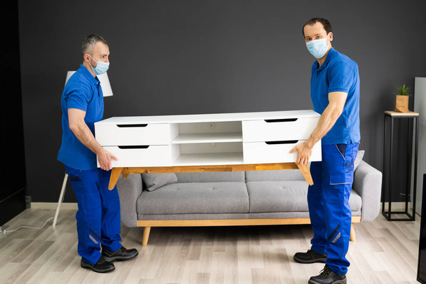 Professional Movers Moving TV Console Furniture In Face Mask - Zdjęcie, obraz
