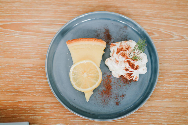 Zitronentarte mit Schlagsahne, in Scheiben geschnitten auf einem weißen Teller. Leckeres, appetitanregendes, hausgemachtes Dessert. Traditionelles französisches Gebäck. - Foto, Bild