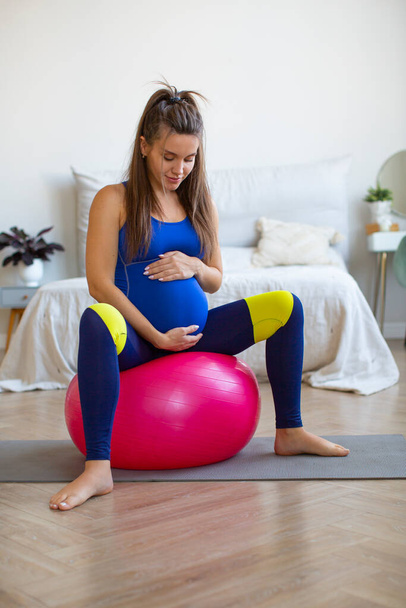 Photo d'une femme enceinte à la maison. Yoga de pilates séance d'entraînement avec balle fitness. - Photo, image