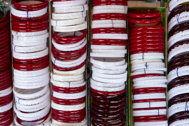 Traditionelle Armreifen Shakha und Paula, ein Paar rote und ein Paar weiße Muschelarmbänder, die von bengalischen Hindu-Braut getragen werden, während sie heiraten. Verkauf in Kalighat, Kalkutta, Indien. - Foto, Bild
