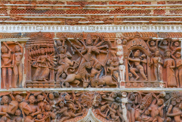 Dekoracje terakoty przedstawiające boginię Durgę, na ścianach świątyni Pratapeswar w Kalnej, Zachodni Bengal, Indie. Terakotowa jest brązowo-czerwoną gliną, która została upieczona i jest używana do wyrobu rzeczy. - Zdjęcie, obraz