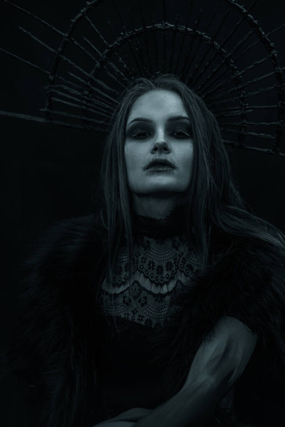 Retrato de jovem mulher na imagem de bruxa em vestido preto e coroa em sua cabeça. - Foto, Imagem