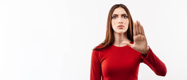 Kuva vakavasta naisesta, jolla on pitkät kastanjahiukset rento punainen pusero, joka tekee stop-merkin kämmenellä. Varoittava ilme kasvoilla. Studion kuva, valkoinen tausta. Ihmisen tunteet käsite - Valokuva, kuva