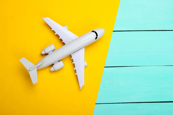 Αεροπλάνο σε κίτρινο, μπλε ξύλινο φόντο. Στο πάνω μέρος. Διακοπές, ταξιδιωτική έννοια - Φωτογραφία, εικόνα